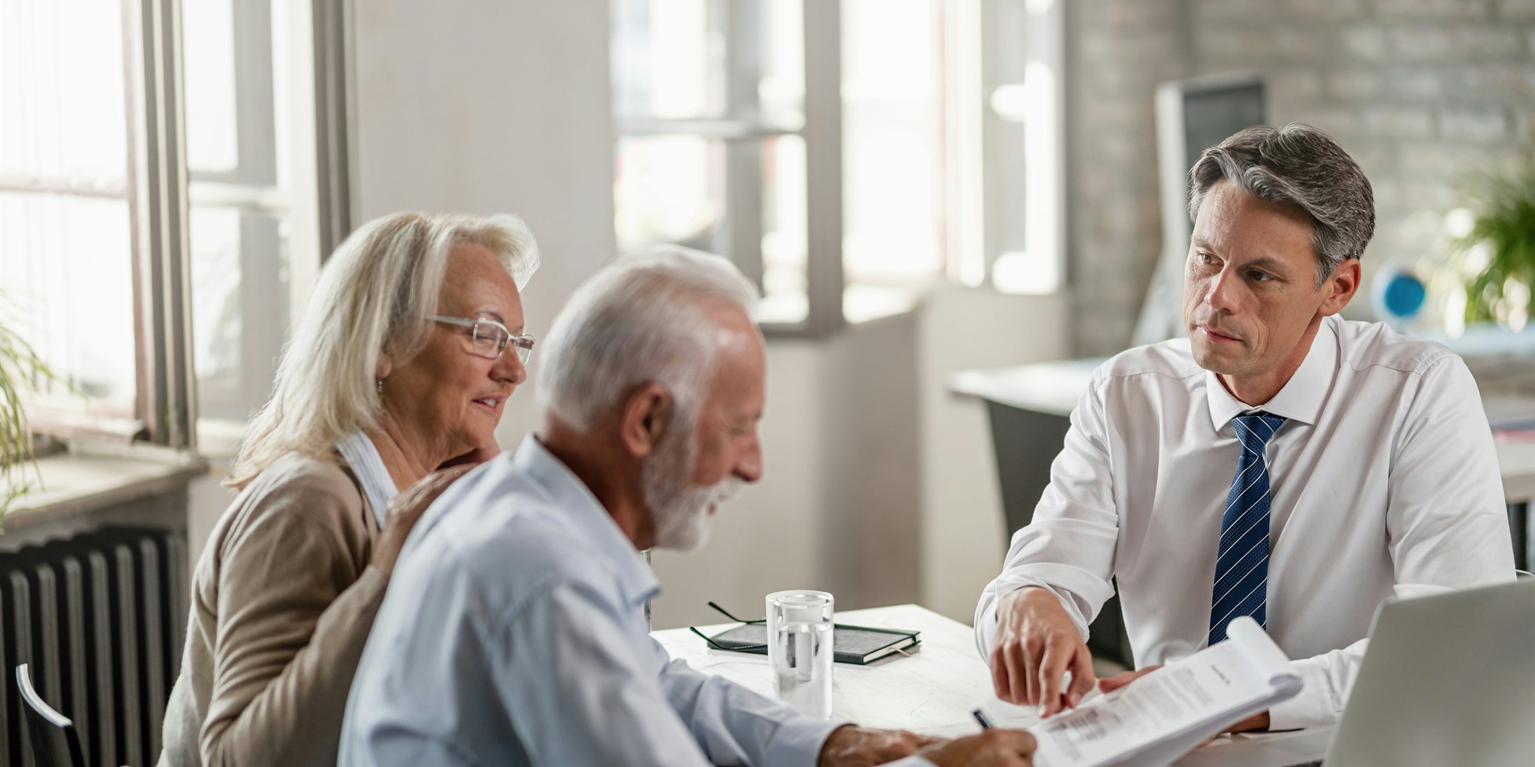 Three people discussing plans around a table